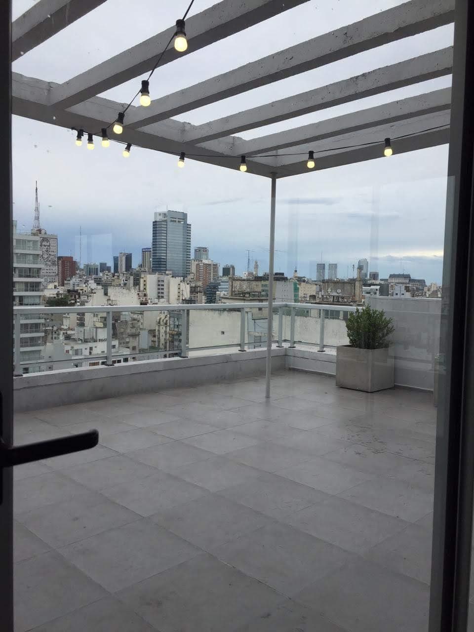 Terraza común con pérgola, luces colgantes y vistas a la ciudad.