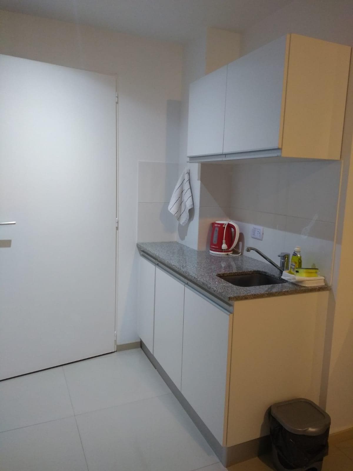 Cocina con mesada, bacha de acero inoxidable y pava eléctrica.
