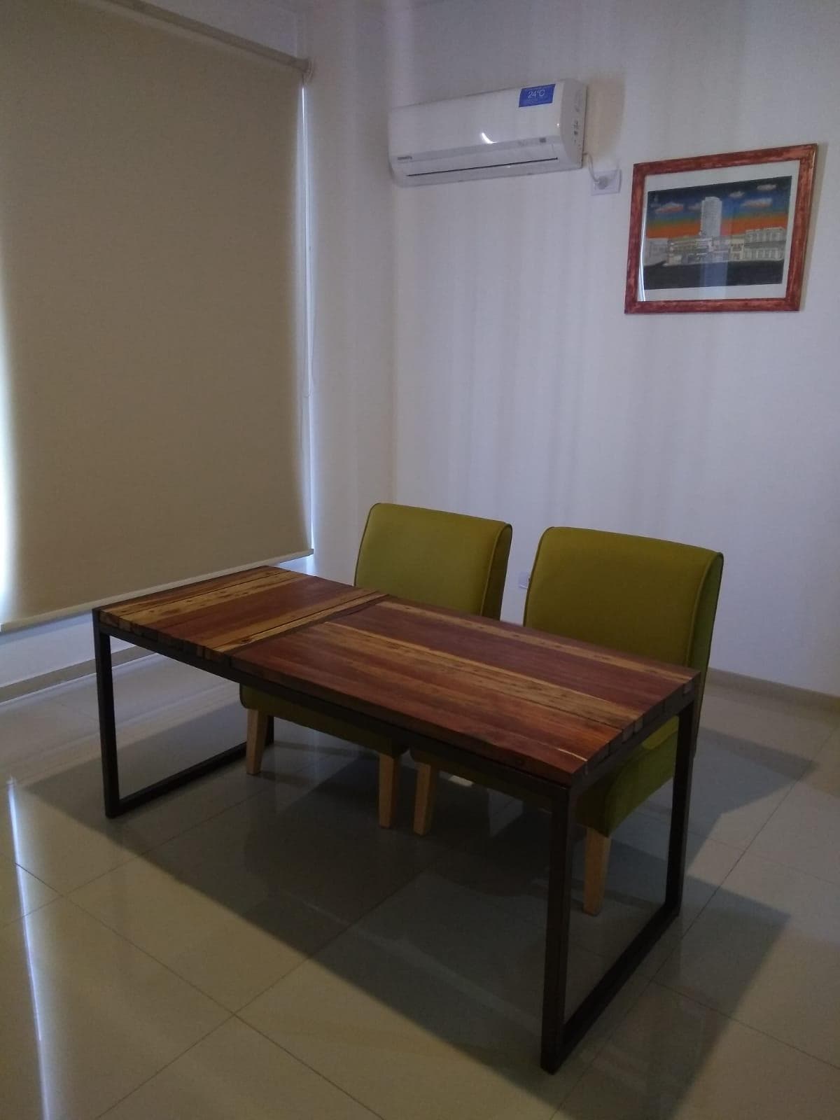 Comedor con mesa rectangular de madera y dos sillas tapizadas en verde.