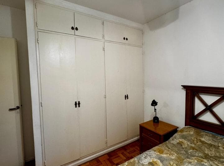 Dormitorio con cama, mesa de luz y un gran placard empotrado blanco.