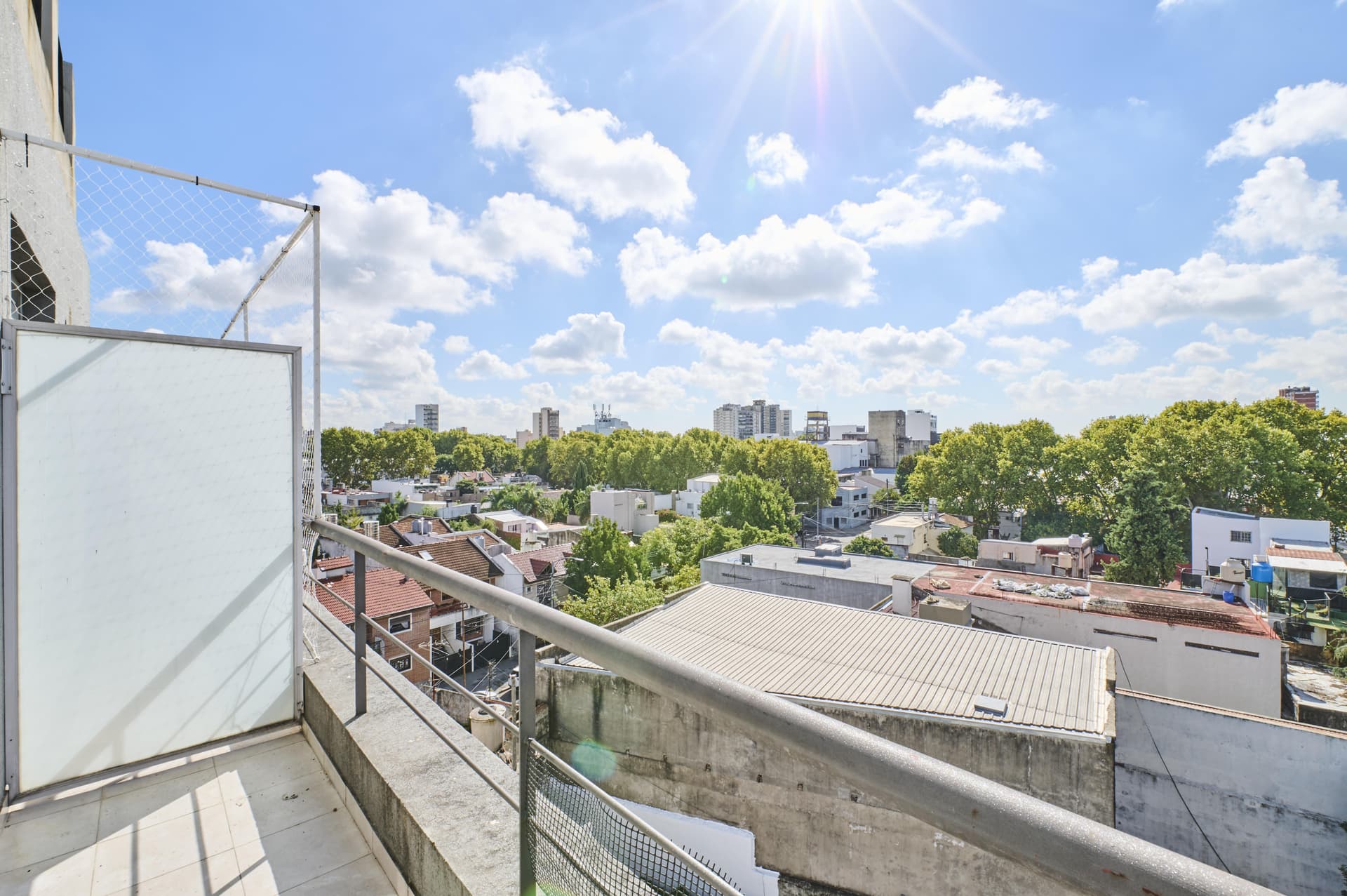 Vista panorámica de la ciudad desde un balcón con cielo soleado.
