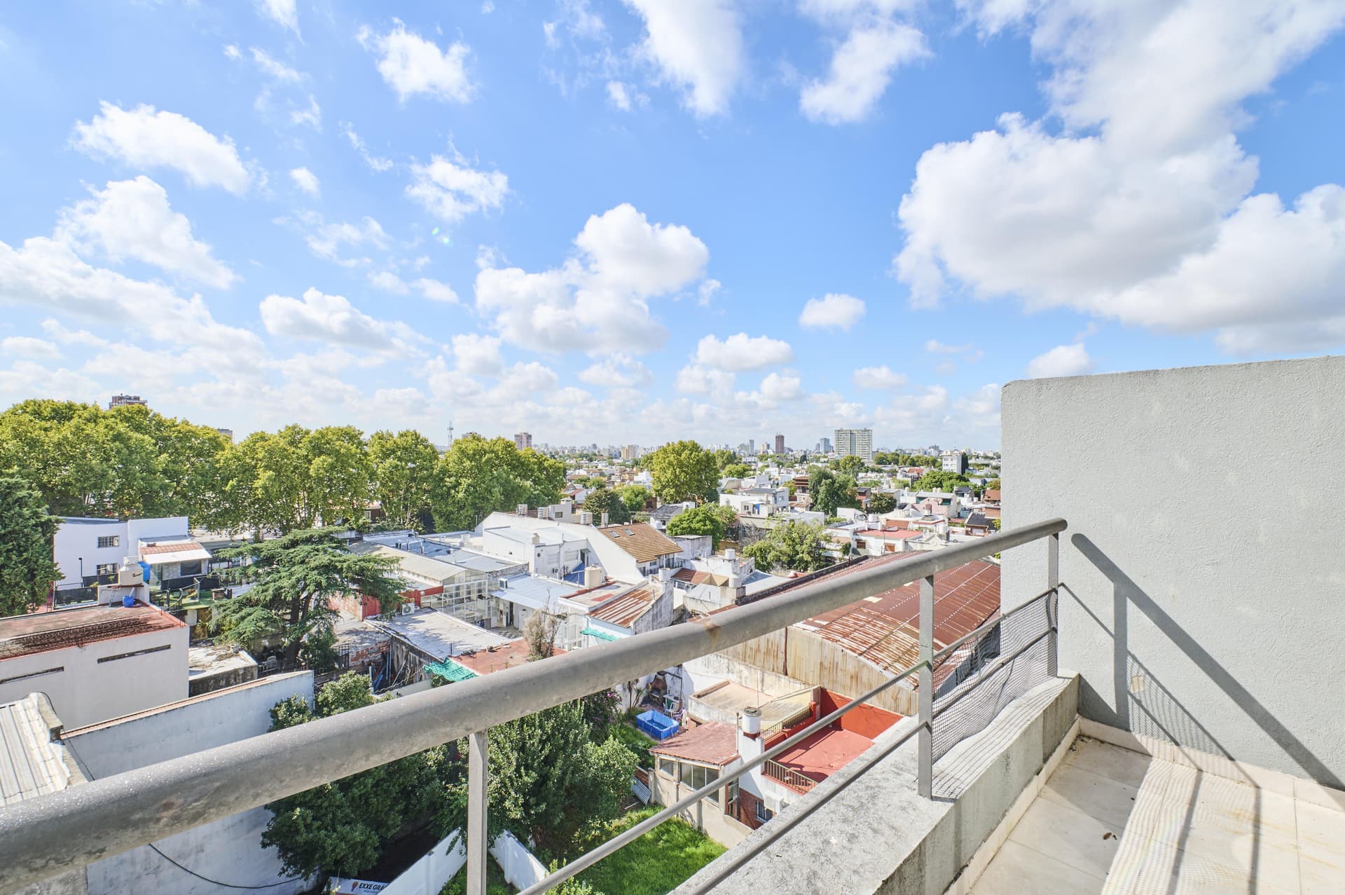 Vista panorámica de la ciudad con edificios, árboles y cielo azul.