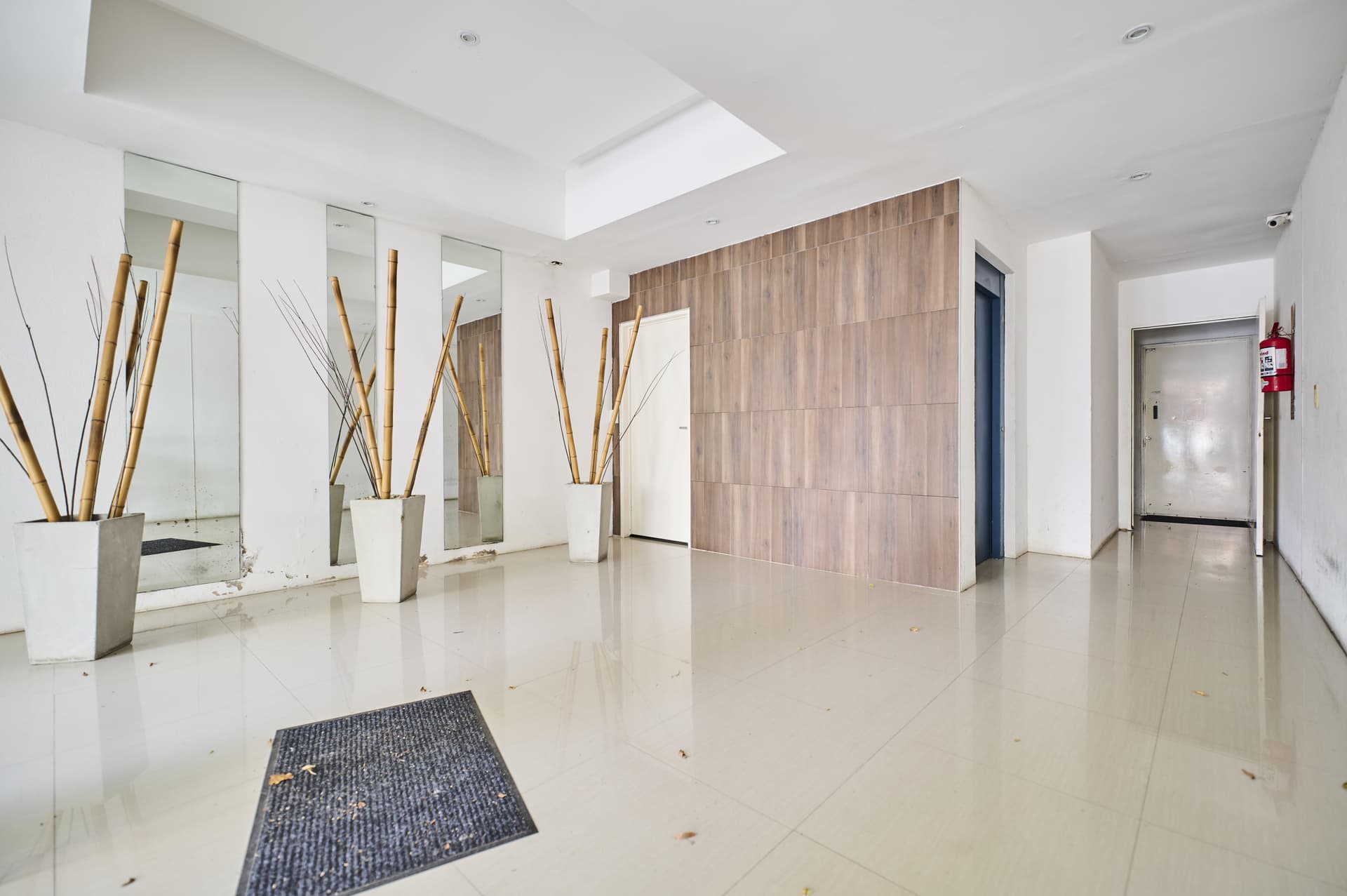 Hall de entrada del edificio con decoración de bambú y espejos.