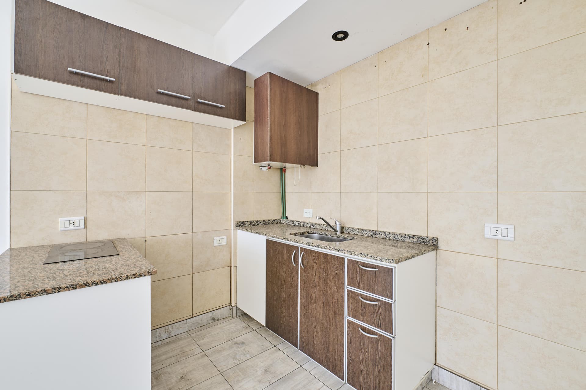 Cocina con mesada de granito, bacha, anafe y alacenas de madera.