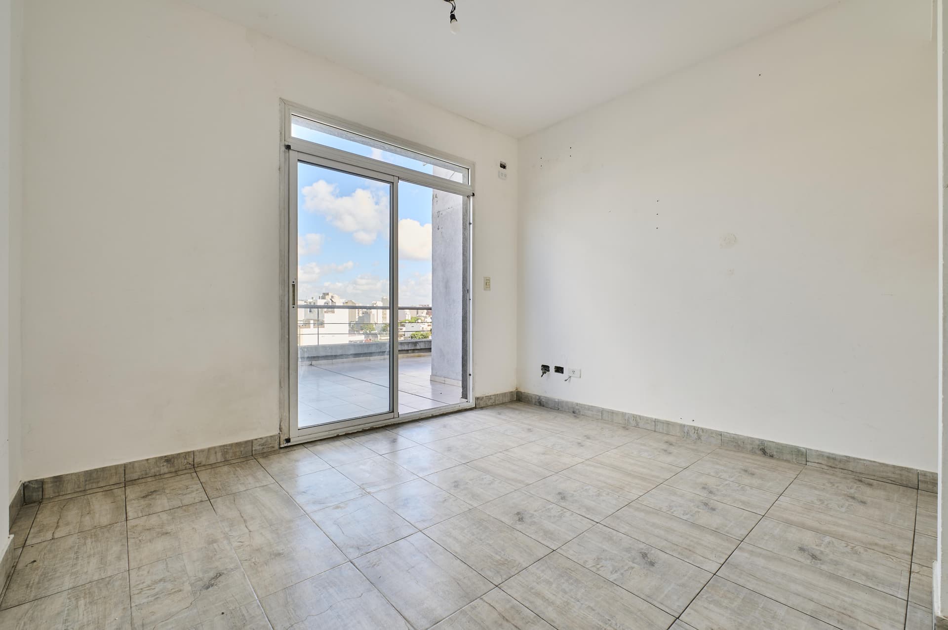 Dormitorio vacío con puerta ventana corrediza, acceso a la terraza.