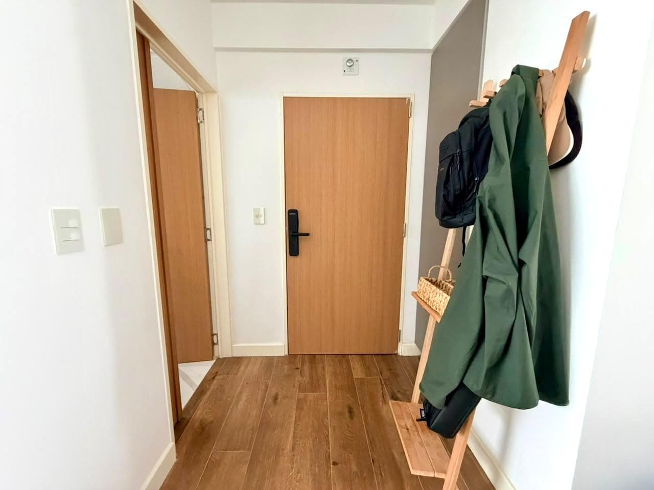 Pasillo de entrada con perchero de madera y piso de parquet.