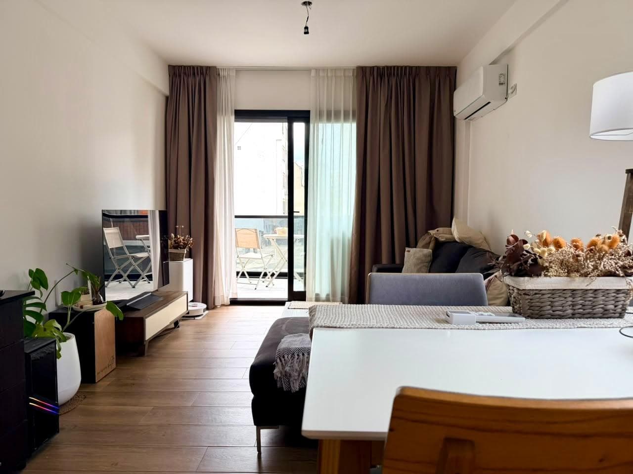 Living comedor con sillón, televisor y acceso al balcón.