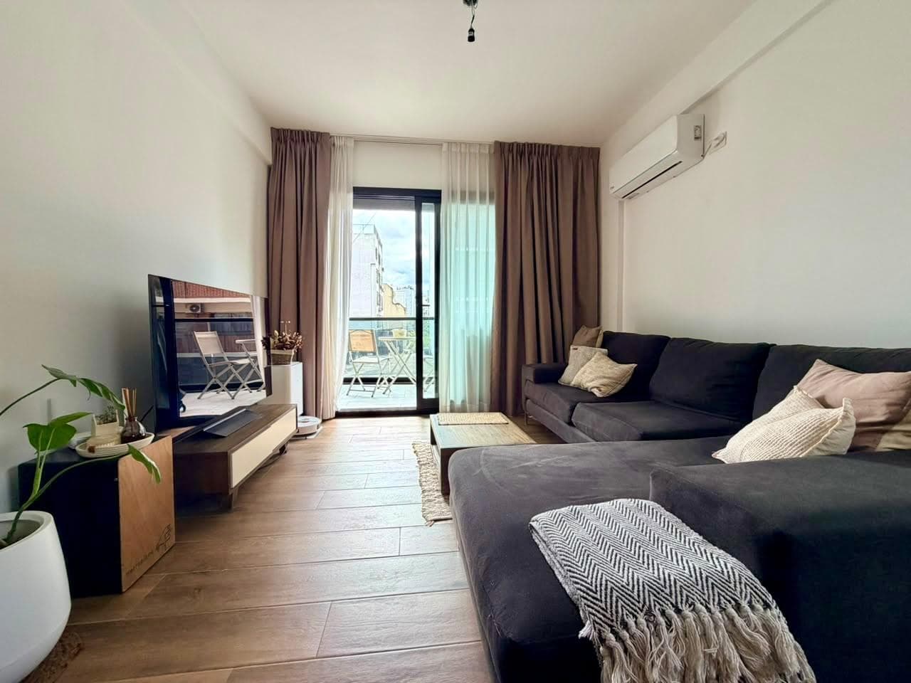 Living con sillón, mesa de centro y televisión frente a la ventana.