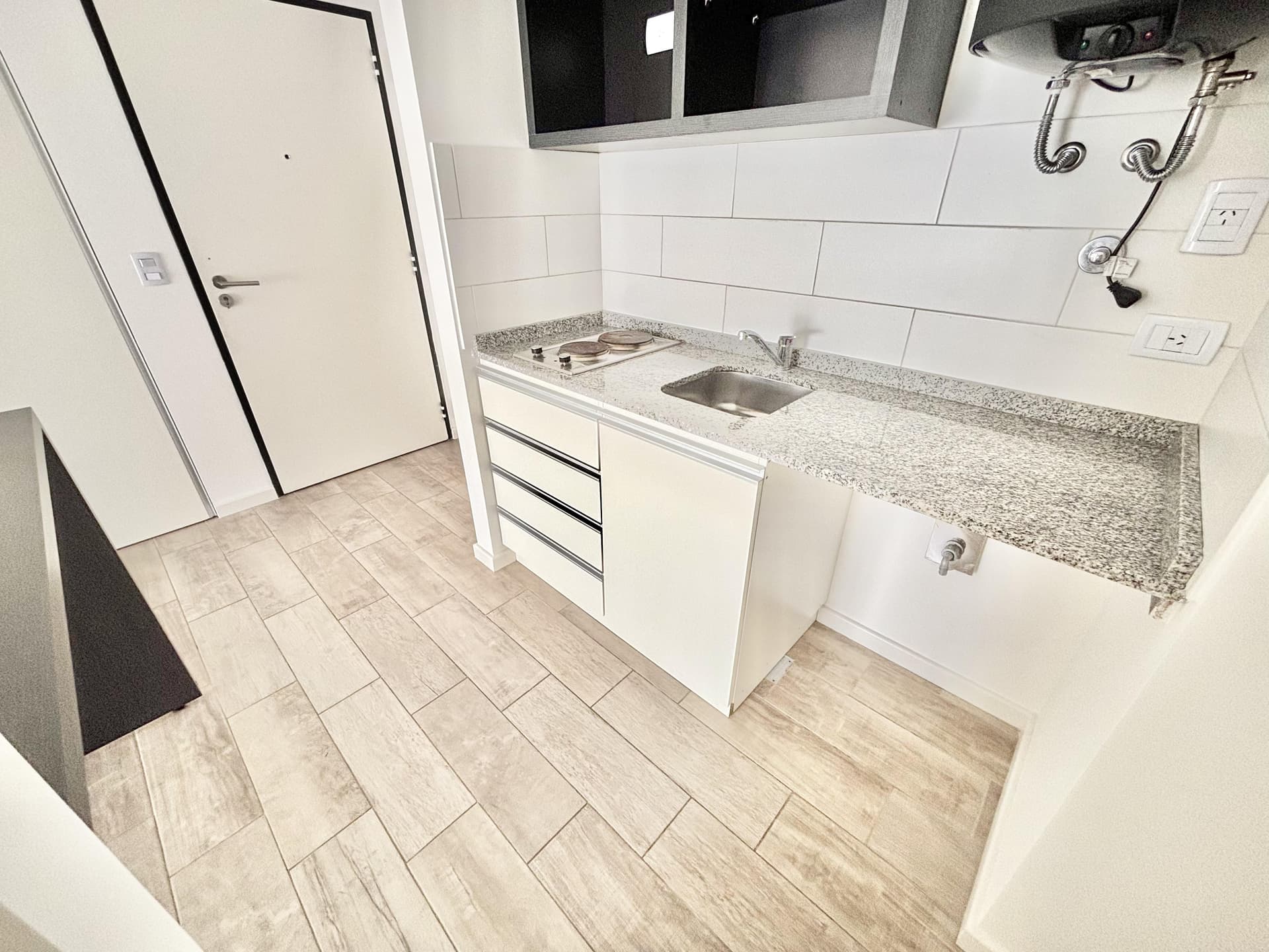 Cocina con mesada, bacha de acero, anafe eléctrico y puerta.