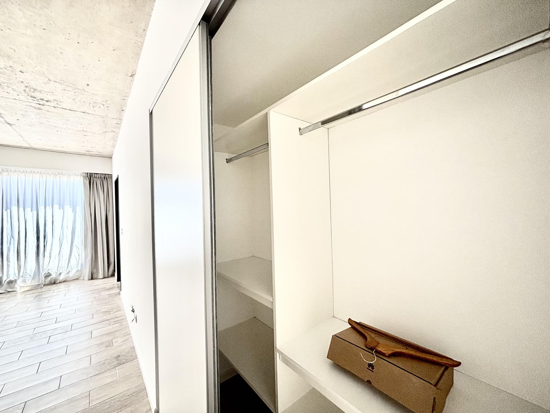 Interior de placard vacío con estantes y barral en un dormitorio.