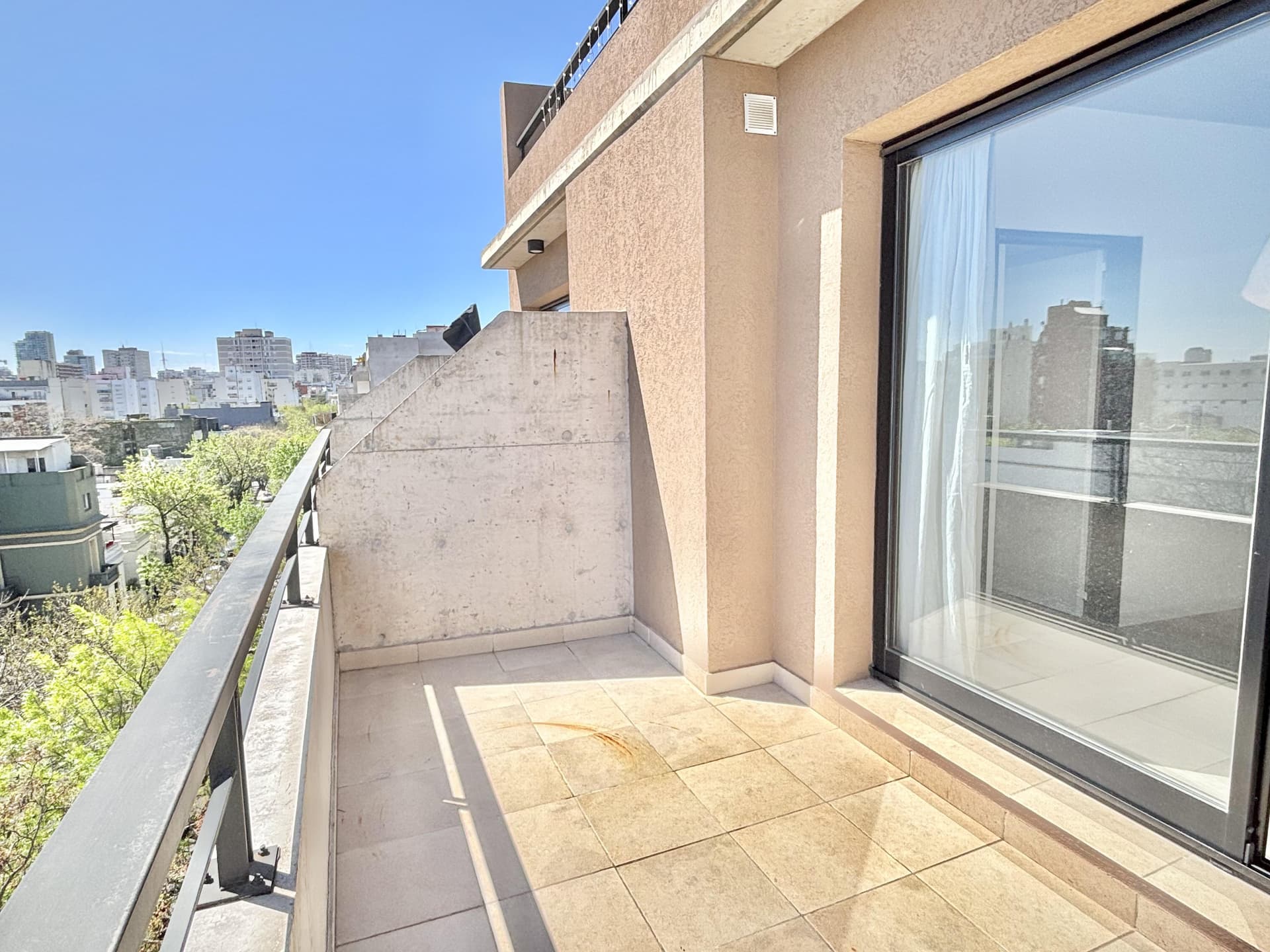 Balcón terraza con piso cerámico y baranda negra.