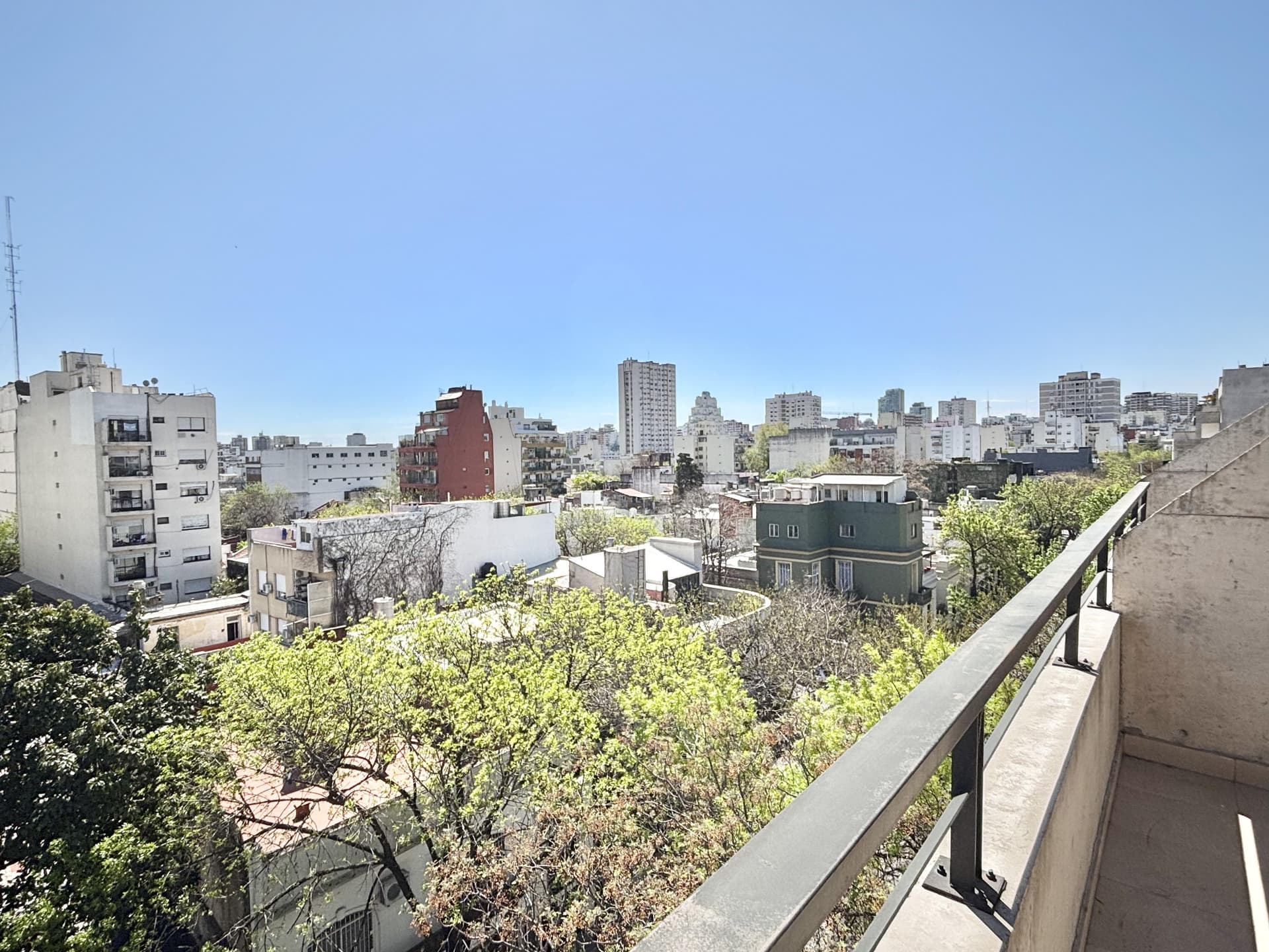 Vista de la ciudad con edificios y arboles verdes desde el balcón.