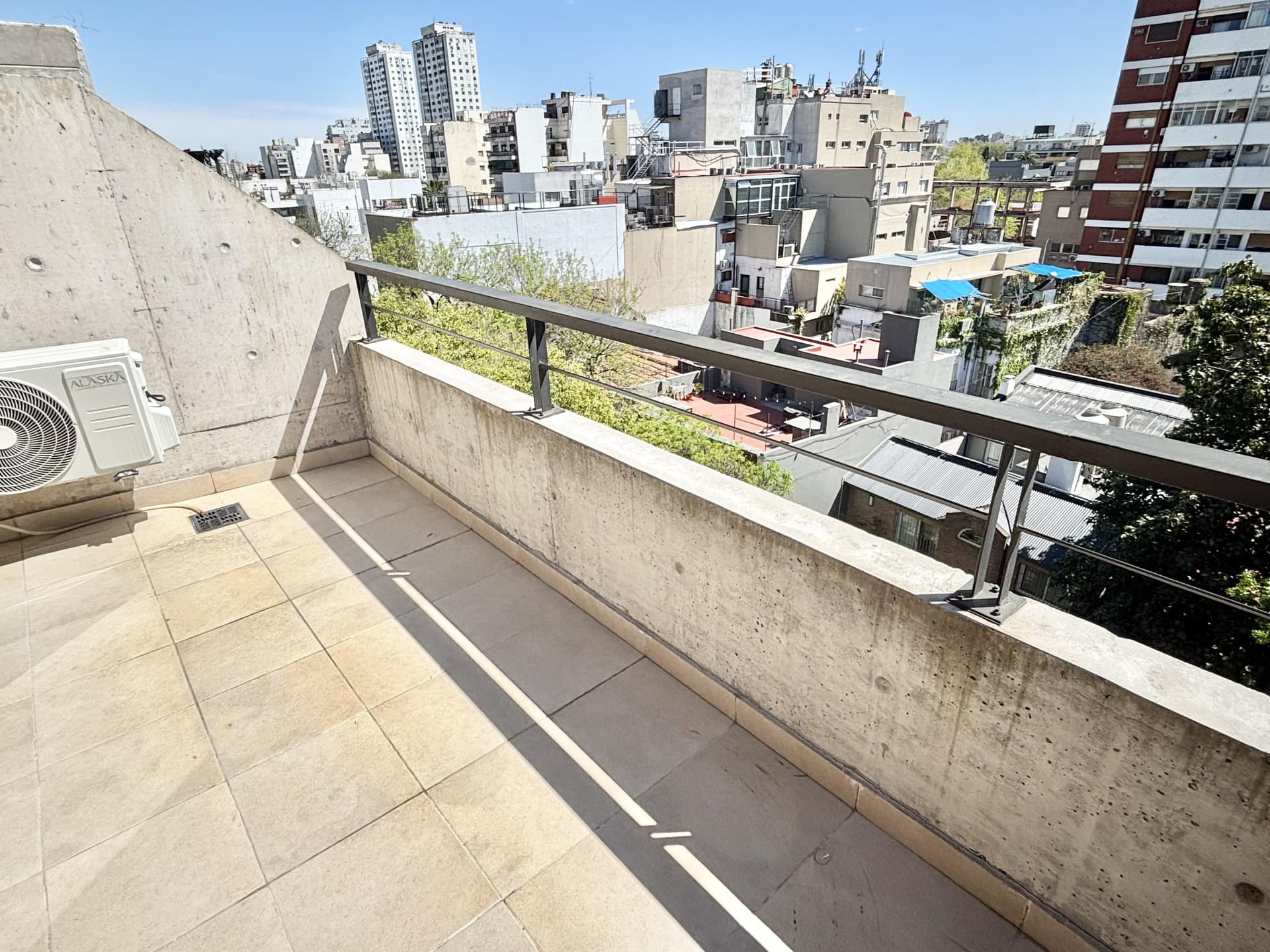 Balcón terraza con unidad exterior de aire acondicionado.