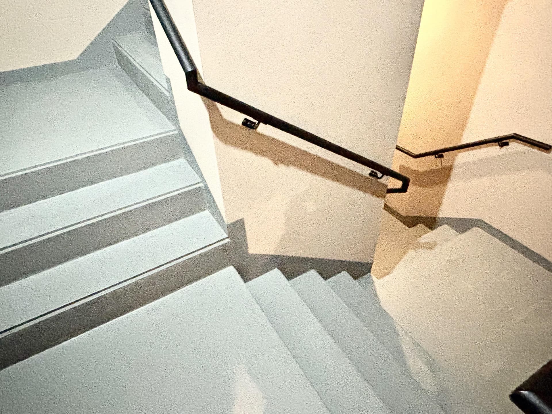 Escalera interior con baranda negra y paredes claras.