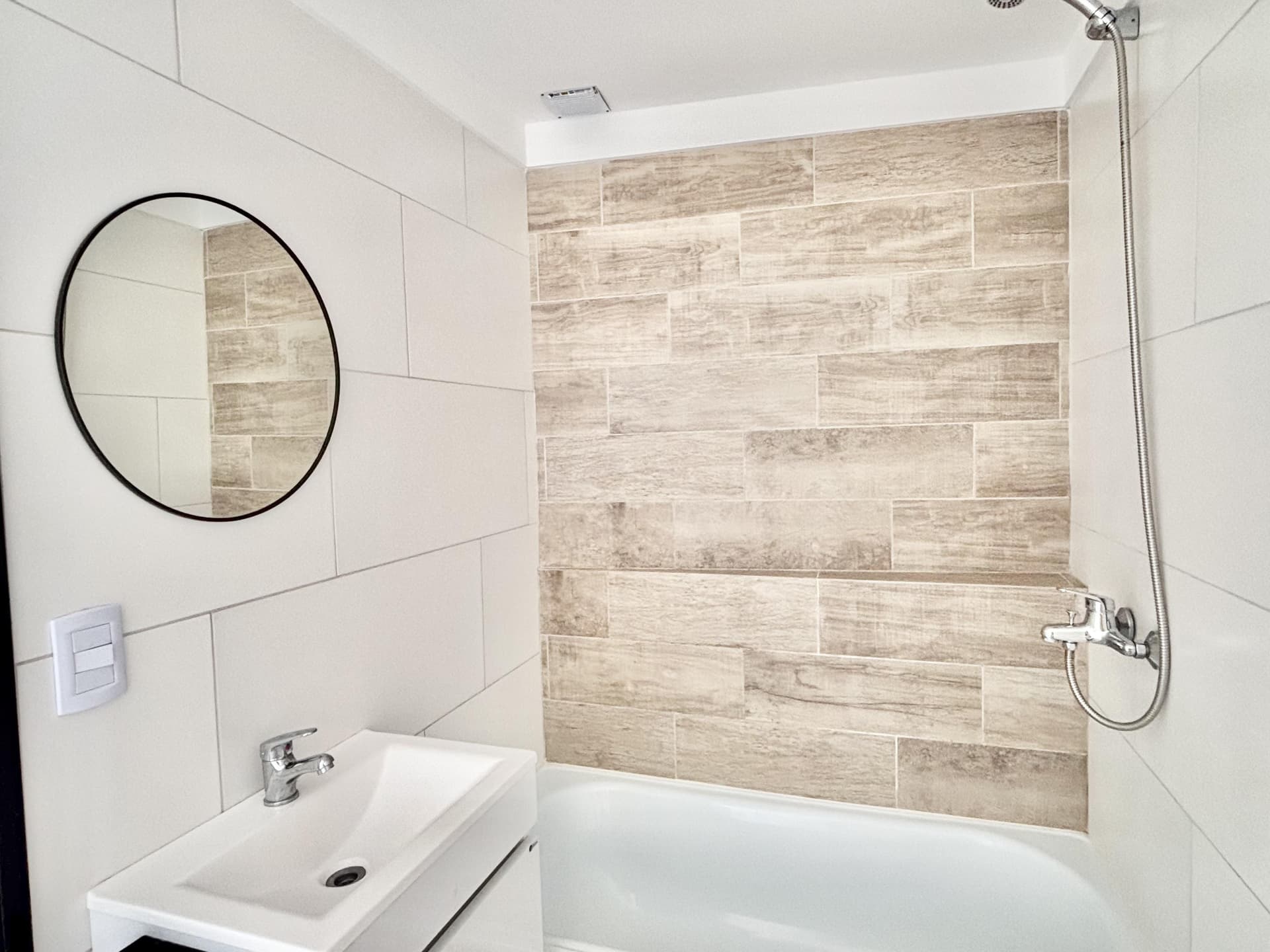 Baño con bañera, ducha, vanitory con grifería monocomando y espejo.