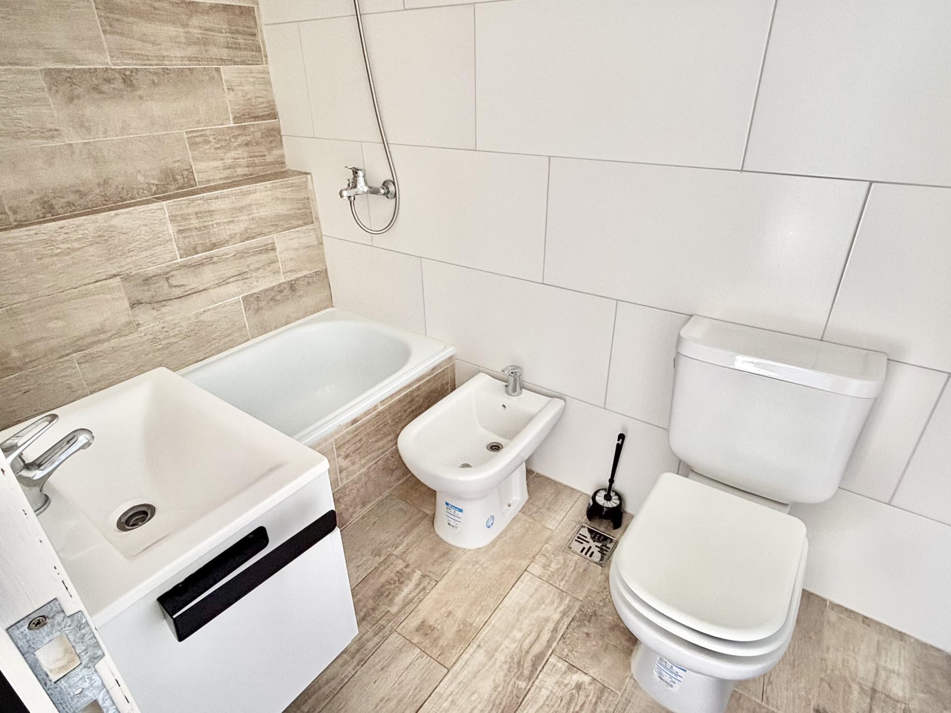 Baño con inodoro, bidet, bañera y vanitory suspendido.