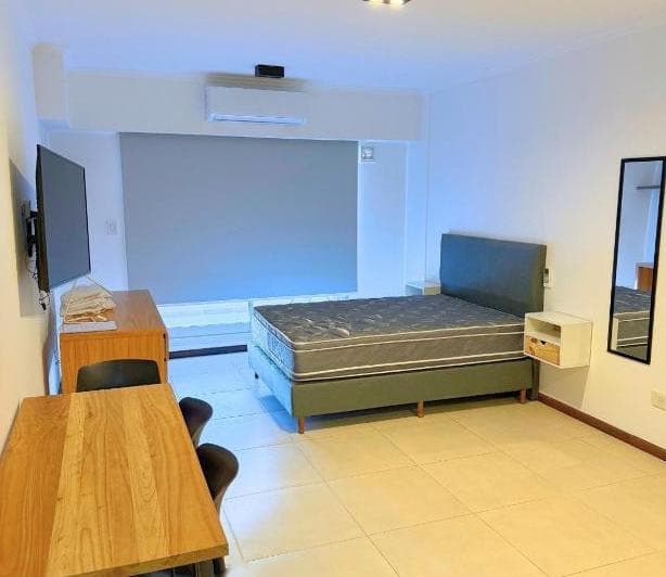 Living amueblado con cama, mesa de comedor y televisor.
