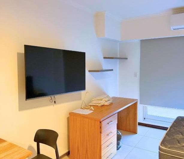Detalle del living con escritorio de madera y televisor.