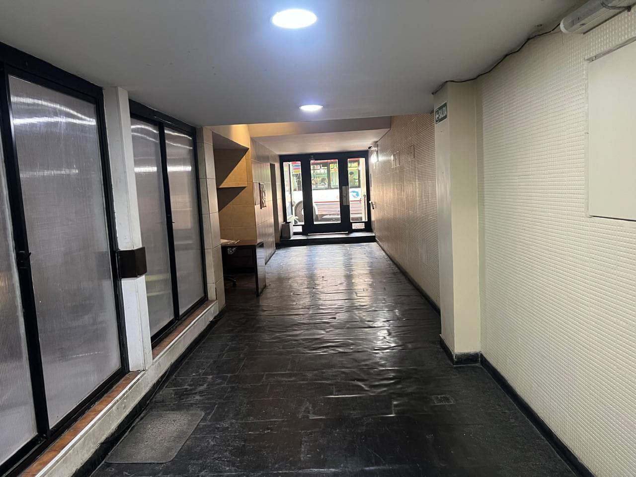 Pasillo interior de un edificio con varios locales comerciales.