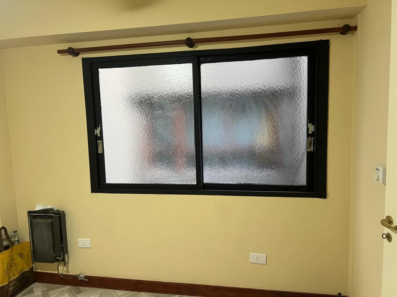 Dormitorio con pared color pastel y una ventana grande.