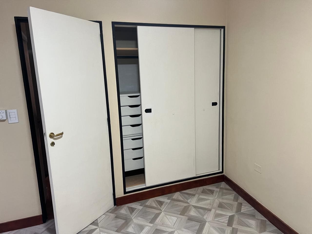 Dormitorio con placard blanco de puertas corredizas y puerta abierta.