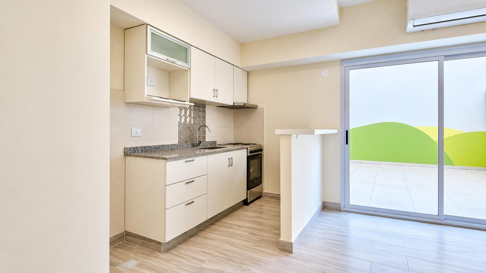 Cocina integrada con muebles blancos, mesada de granito, horno y salida exterior.
