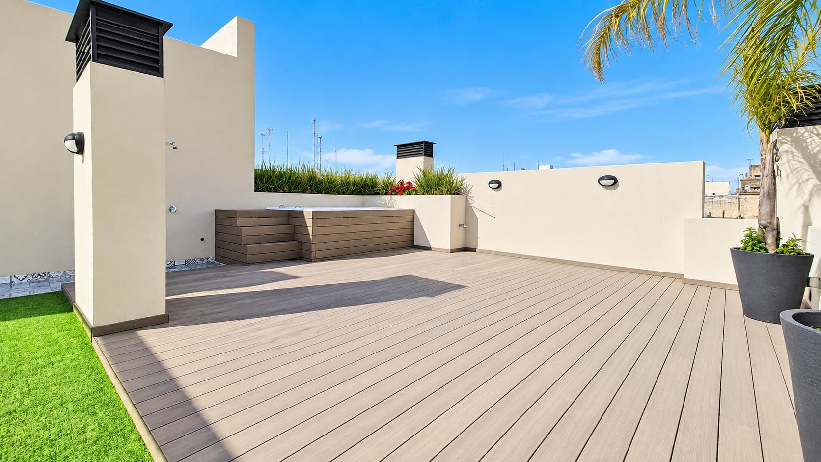 Terraza con deck de madera, jacuzzi en la esquina y césped sintético.