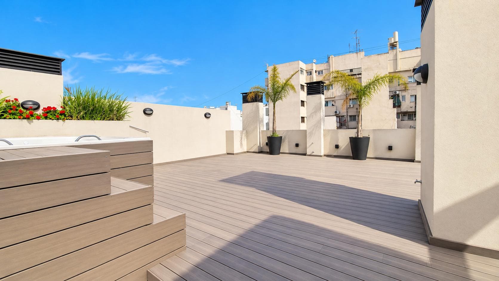 Terraza amplia con deck de madera, jacuzzi y cielo azul despejado.