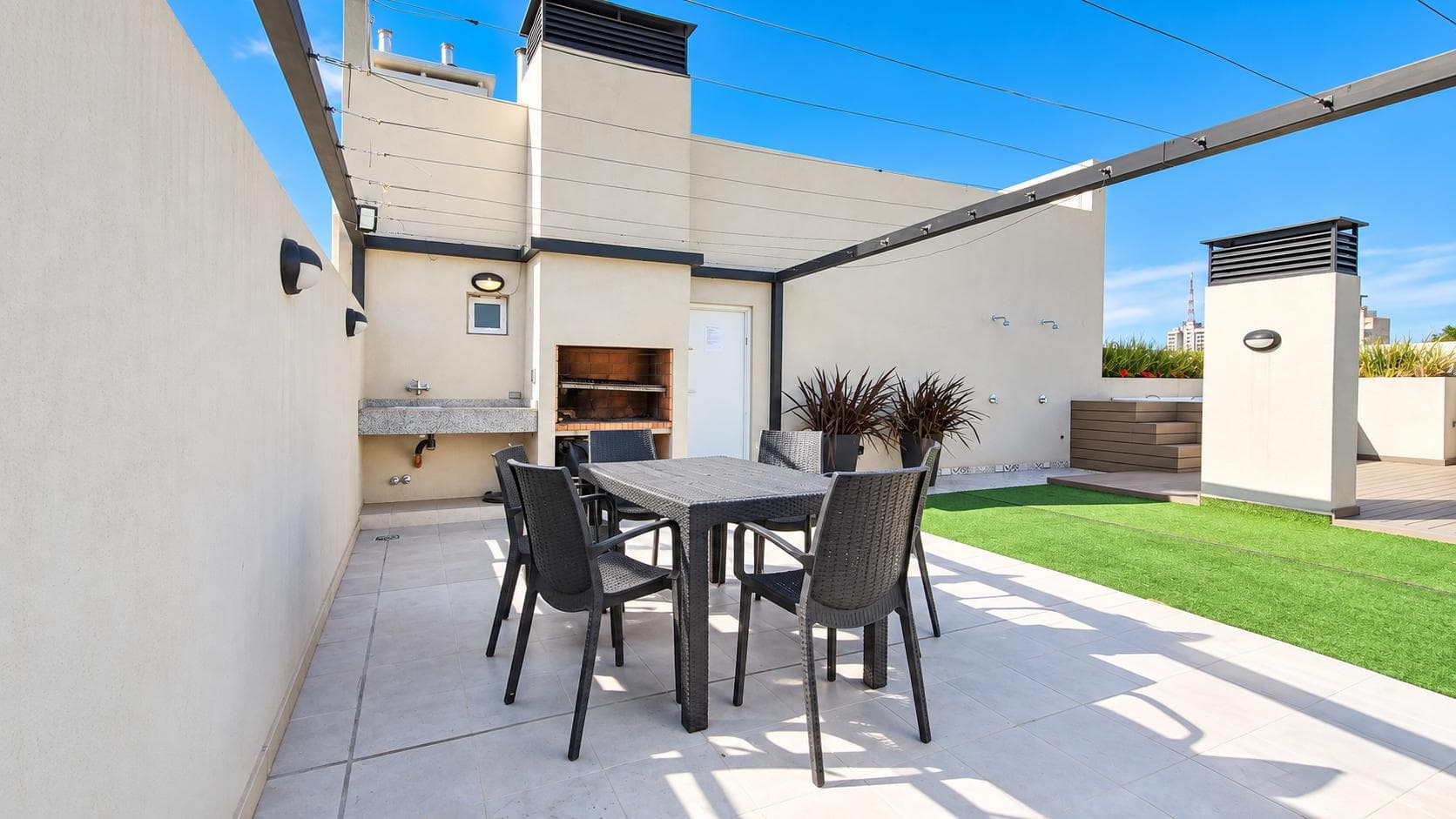 Terraza con parrilla, mesa exterior, césped sintético y jacuzzi.
