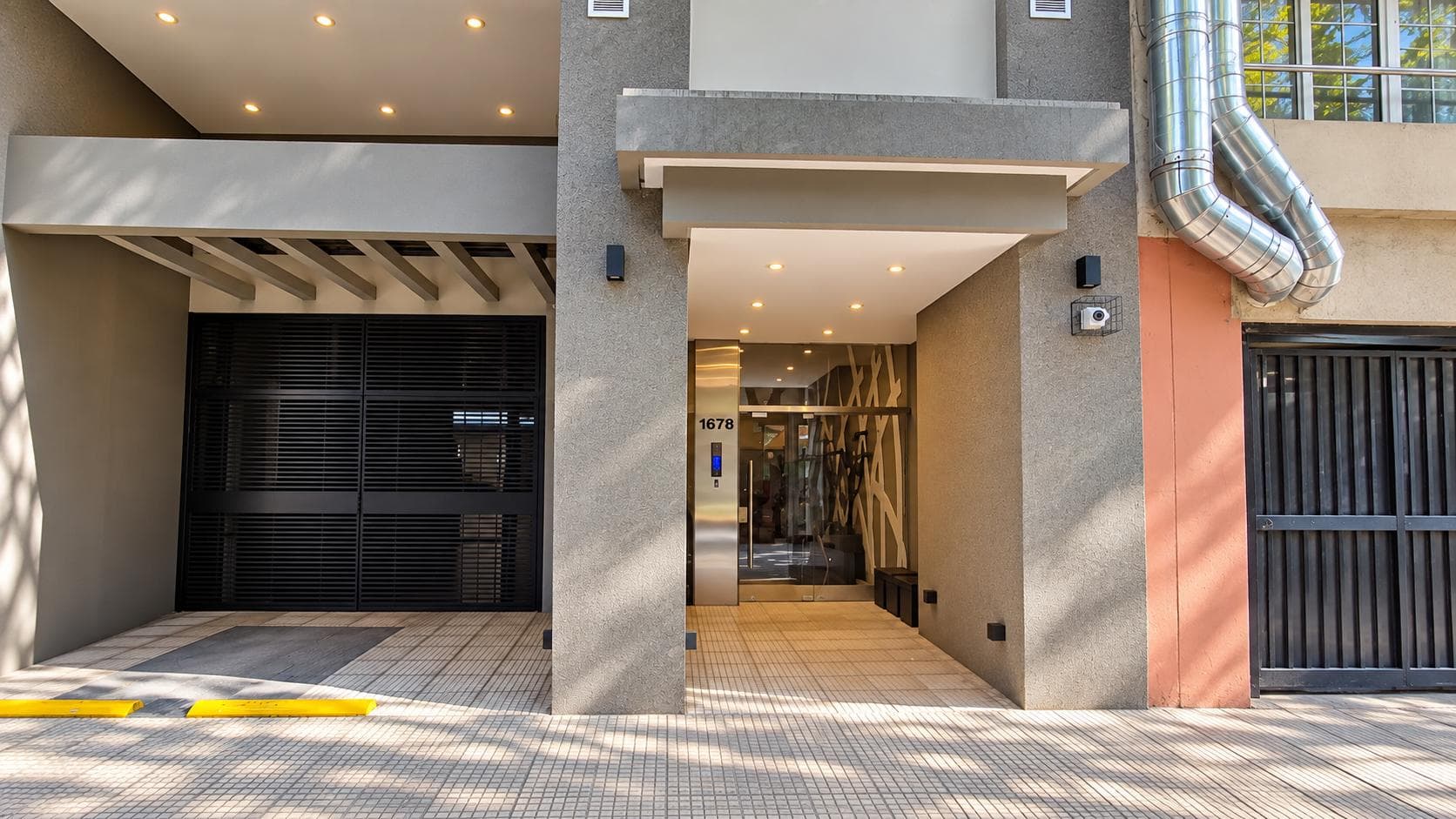 Fachada moderna de edificio con entrada principal y portón de garaje negro.