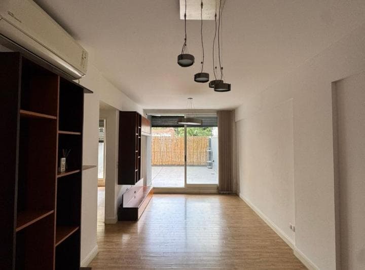 Amplio living vacío con piso de madera y salida exterior con cerco de cañas