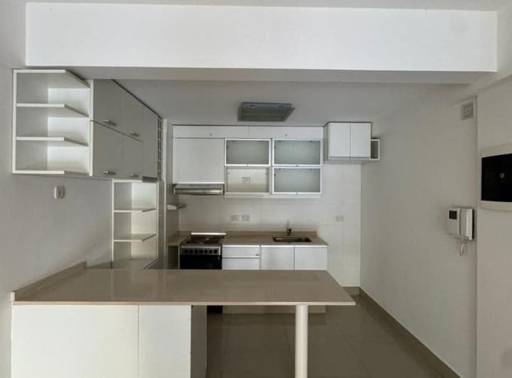 Cocina integrada con mesada, anafe, bacha y alacenas blancas