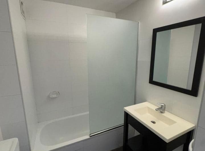Baño con bañera, mampara de vidrio y lavatorio con espejo