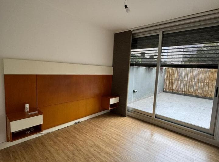 Dormitorio con cabecera de cama de madera y salida a patio o balcón