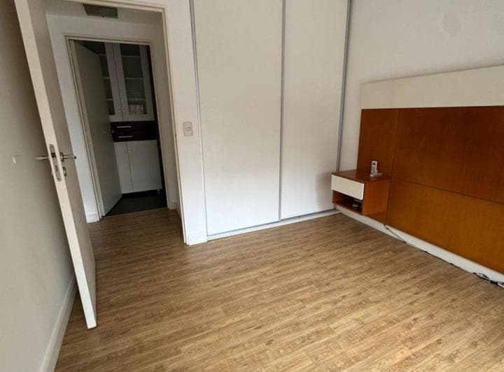 Dormitorio con placard blanco y cabecera de cama de madera