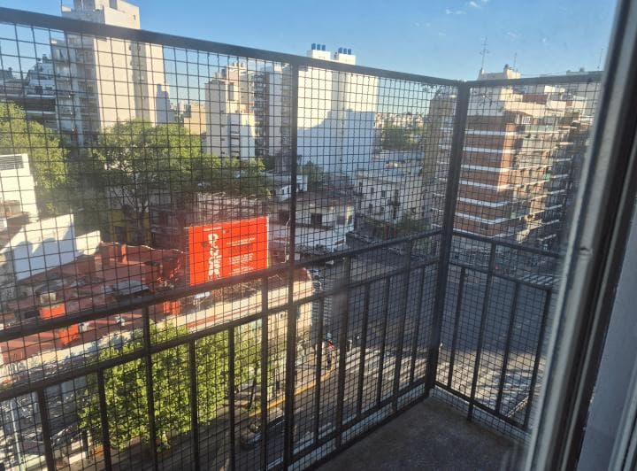Balcón enrejado con vista panorámica a la ciudad y edificios.