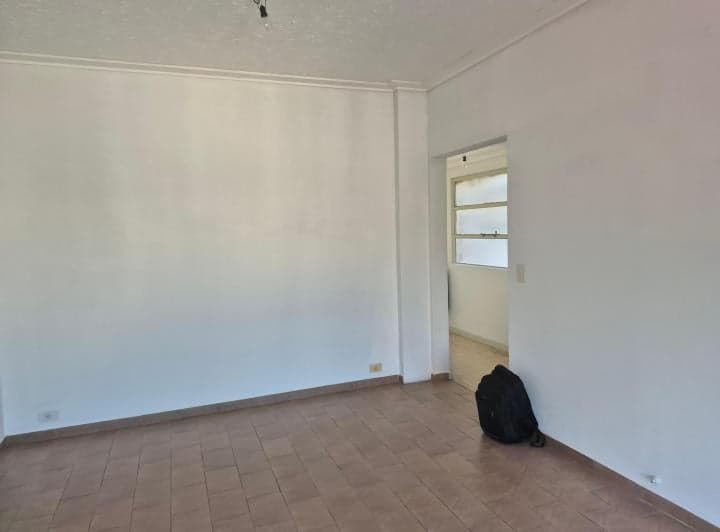 Living vacío con piso de cerámica y una puerta que conduce a otra habitación.