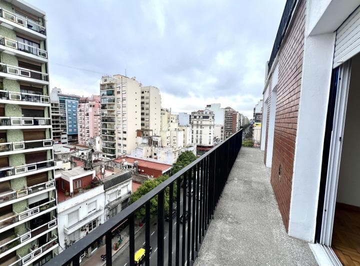 Balcón largo con baranda de hierro y vista panorámica a la ciudad.