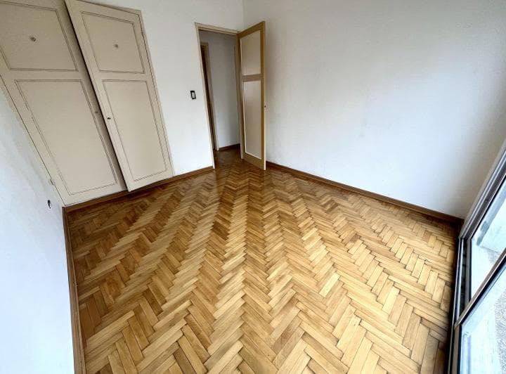 Dormitorio vacío con piso de madera, placard empotrado y puerta abierta.
