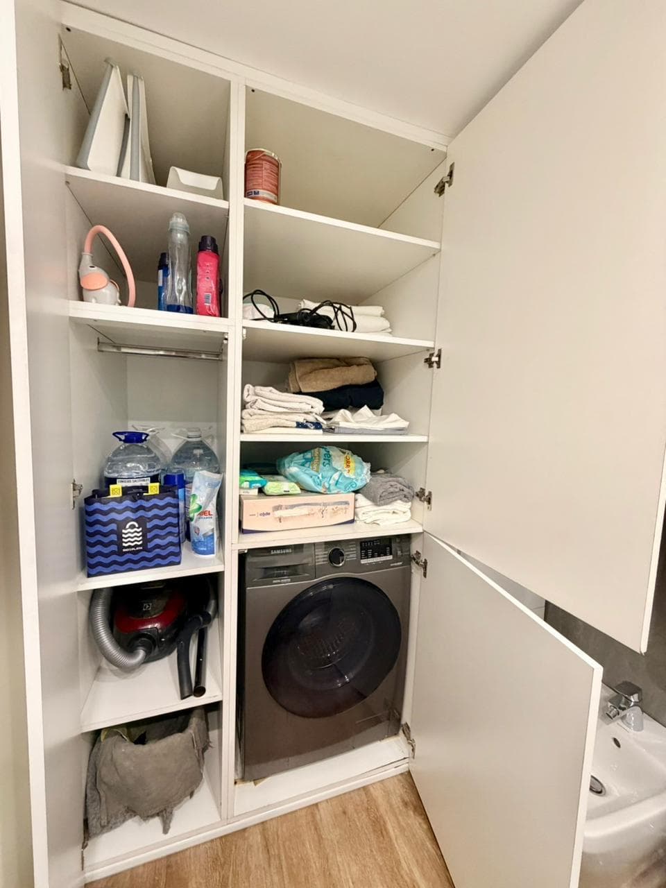 Lavadero con lavarropas integrado en mueble, estantes y pileta de lavar.