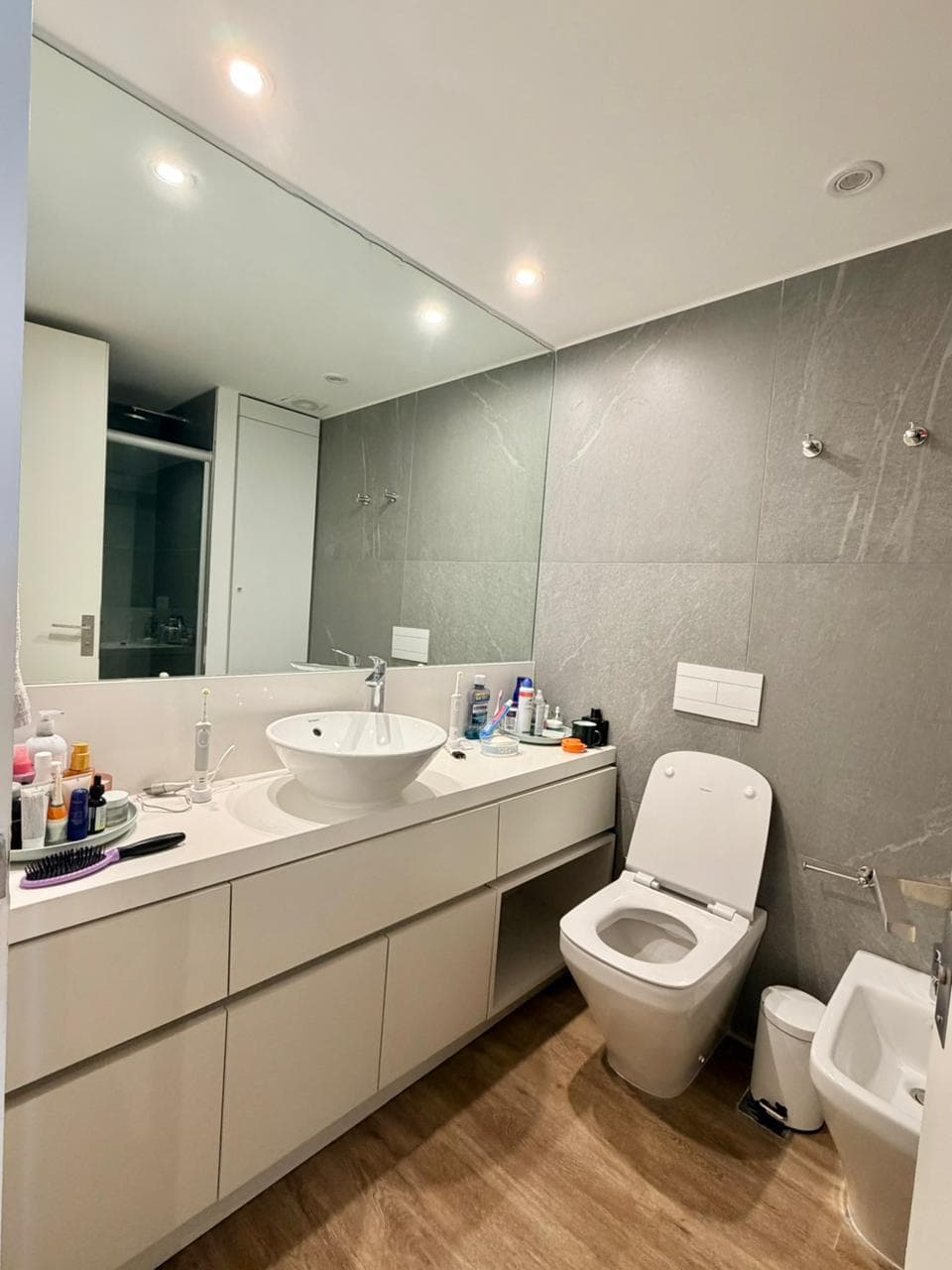 Baño moderno con bacha, inodoro, bidet, espejo y ducha con mampara.