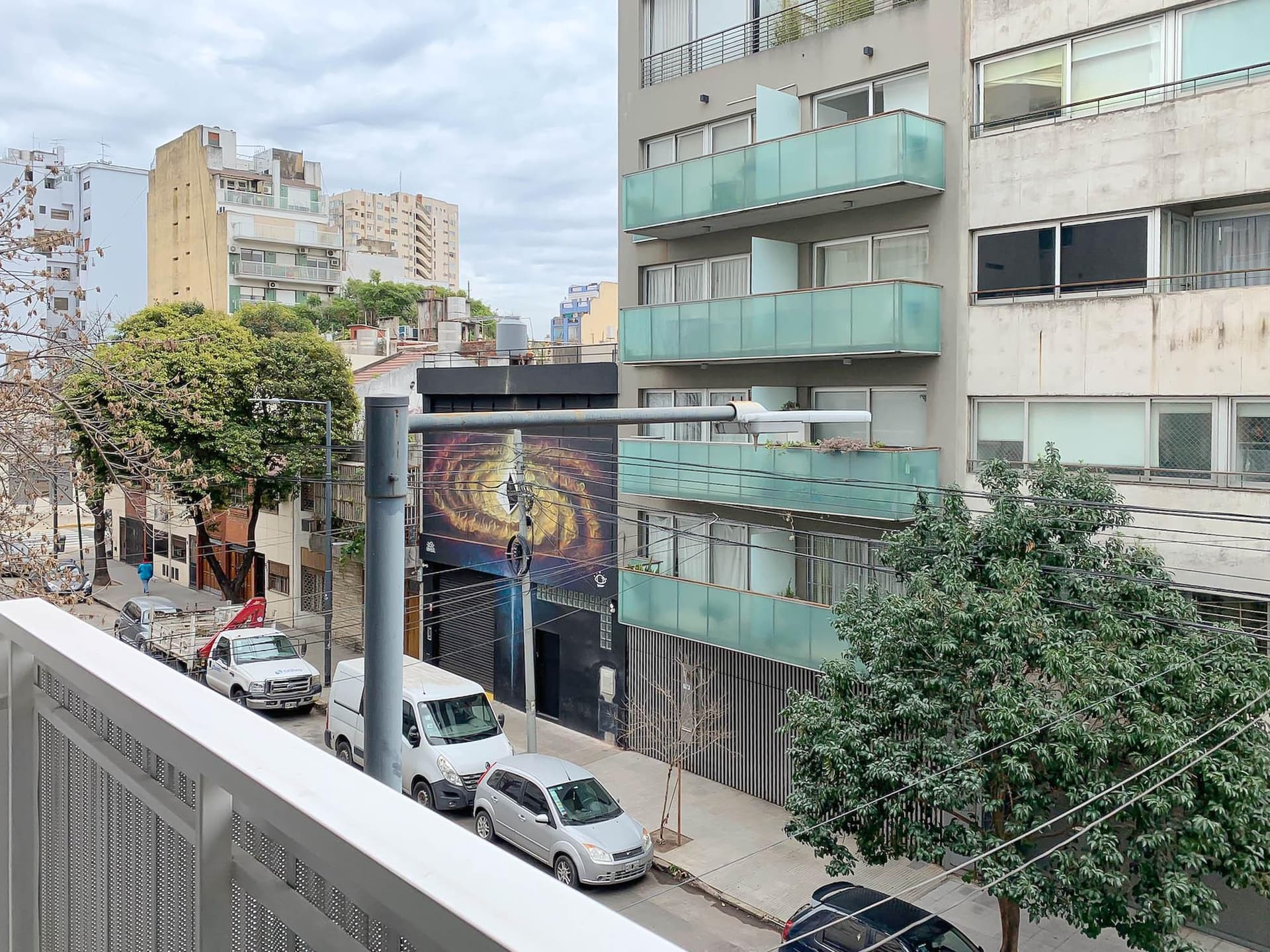 Vista desde el balcón a la calle con autos y edificios.