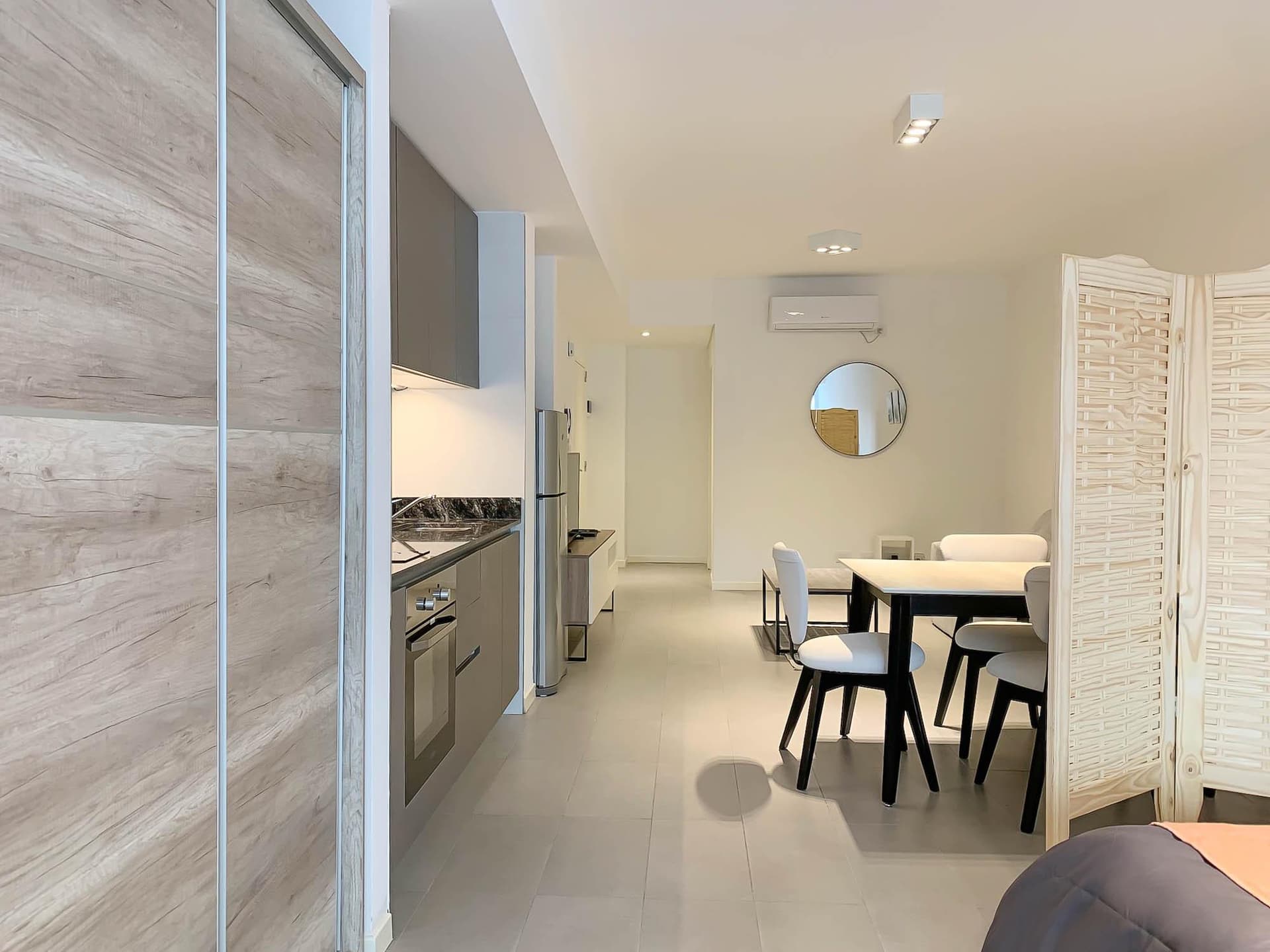 Cocina integrada con heladera, mesa de comedor y biombo.
