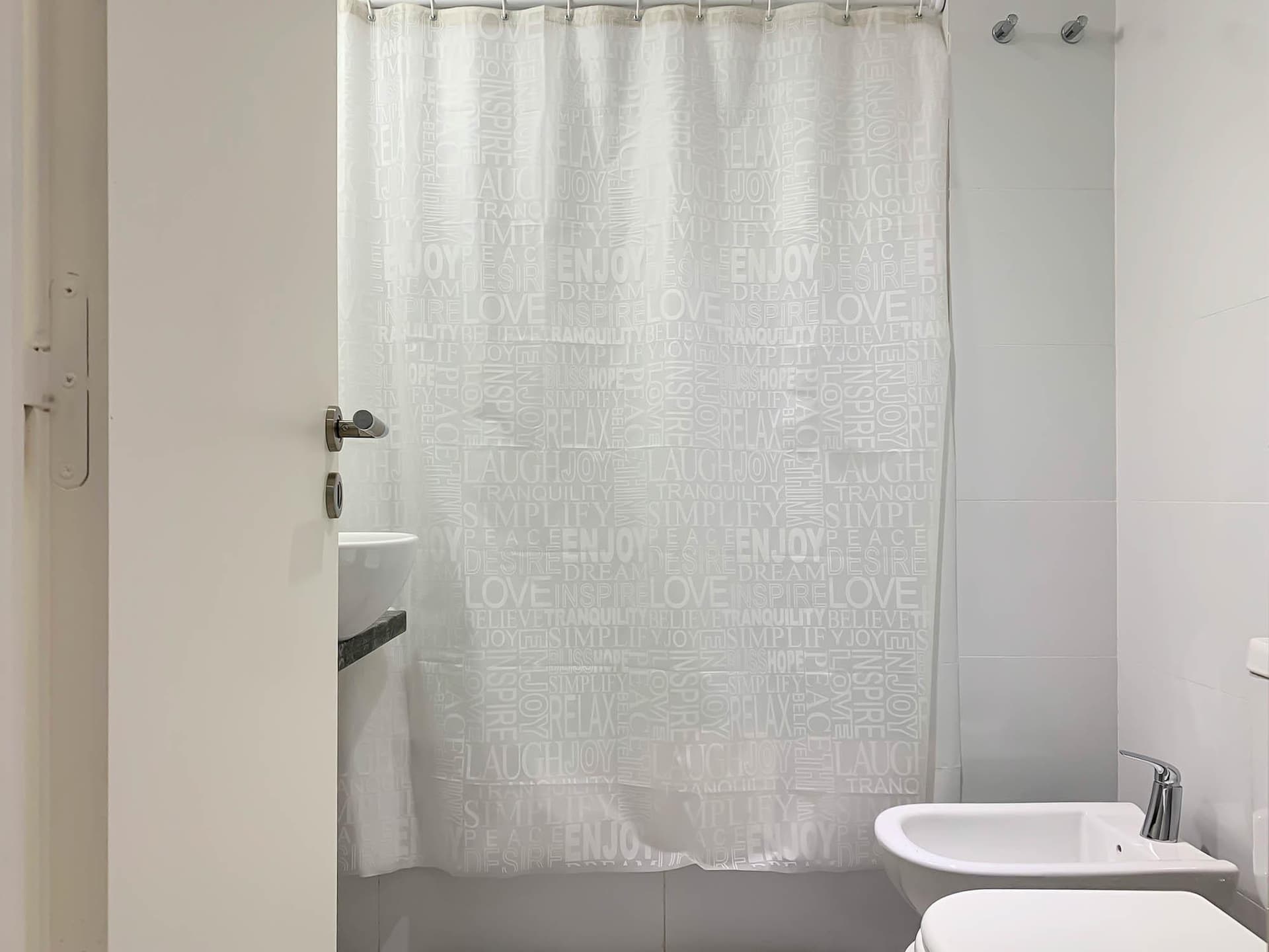 Baño con cortina de ducha, inodoro, bidet y lavatorio de bacha.