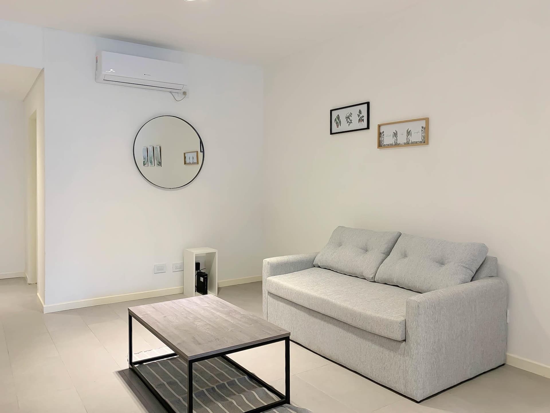 Living con sofá, mesa de centro, espejo y aire acondicionado.