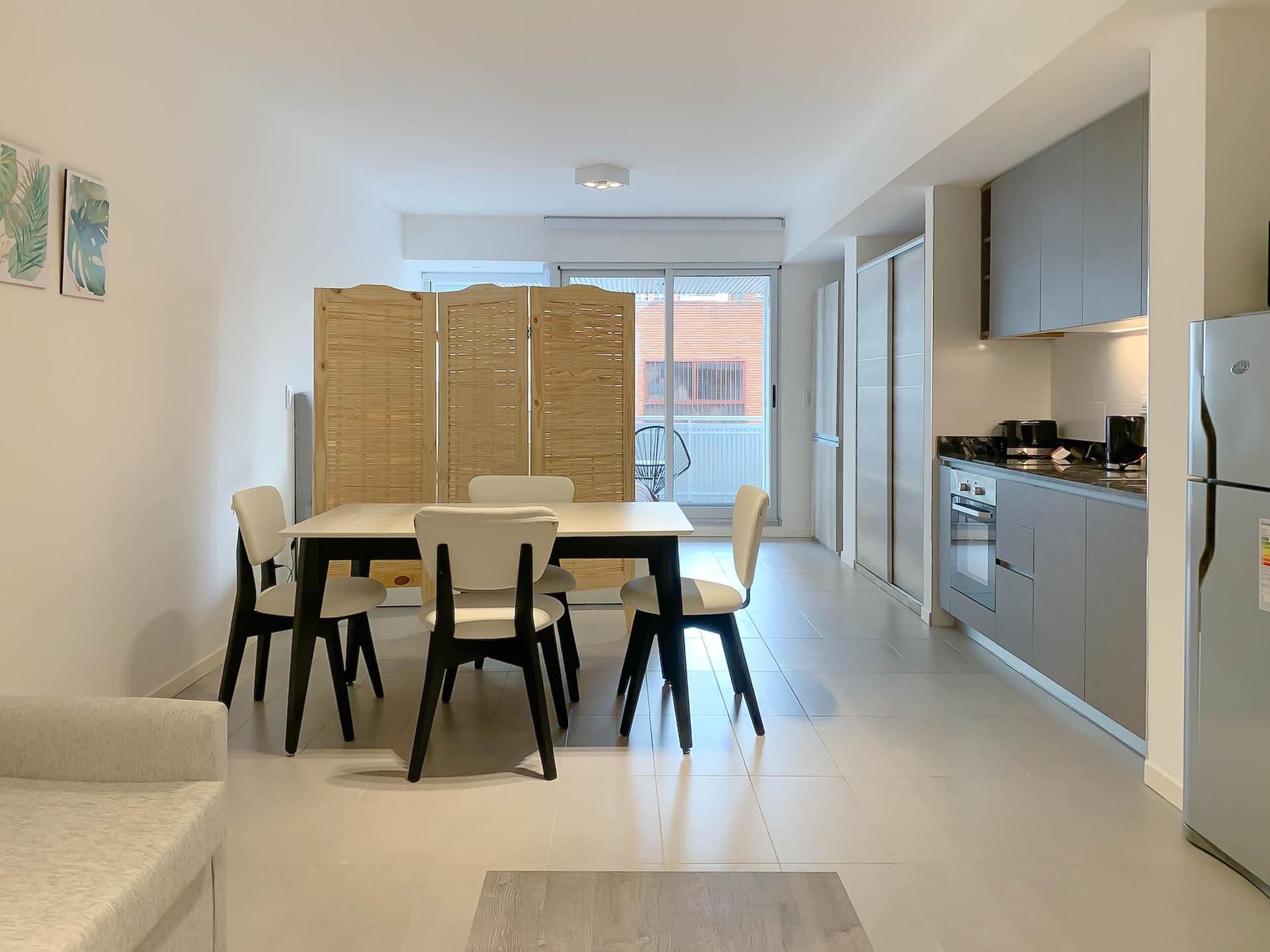 Living con mesa de comedor y cocina integrada, biombo y heladera.