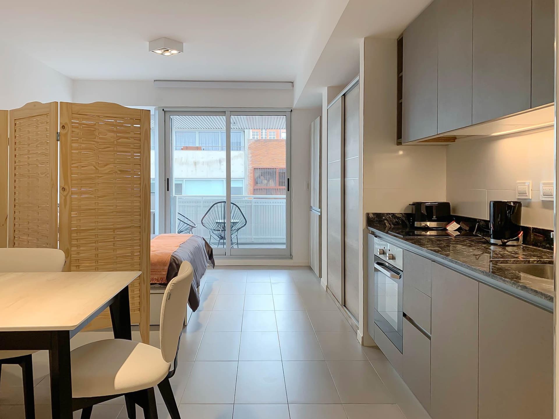 Cocina integrada con anafe, mesada, armarios y vista al balcón.