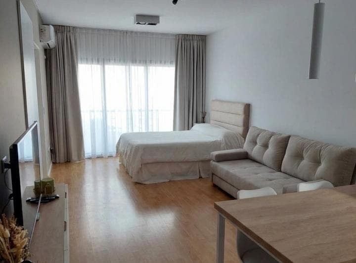 Dormitorio con cama de dos plazas, sillón y ventanal con cortinas.