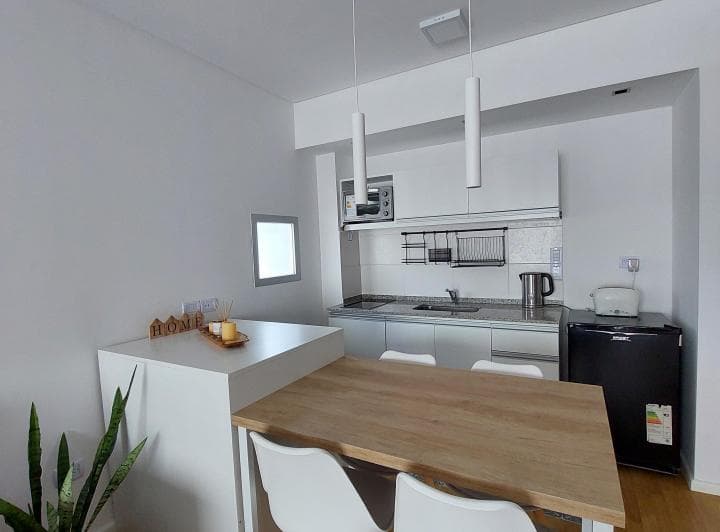 Cocina integrada con mesada, bacha, anafe, heladera y mesa de comedor.