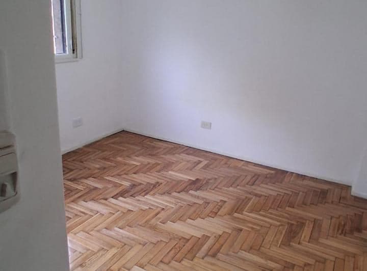 Dormitorio vacío con piso de parquet y ventana.